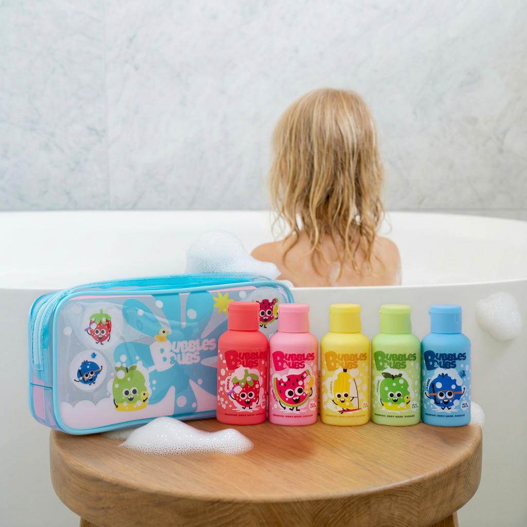 bubbles and bubs travel size pack - shampoo, body wash and bubbles 3 in 1 formula, five scents and girl having a bath on the background looking away form the camera