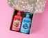 Two bottles of bubbles and bubs shampoo, body wash and bath bubbles in presented in an open gift box with a playful pattern.playful box, Rosie the watermelon and Berry the blueberry playful character designs, 