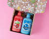 Two bottles of bubbles and bubs shampoo, body wash and bath bubbles in presented in an open gift box with a playful pattern.playful box, Rosie the watermelon and Berry the blueberry playful character designs, 